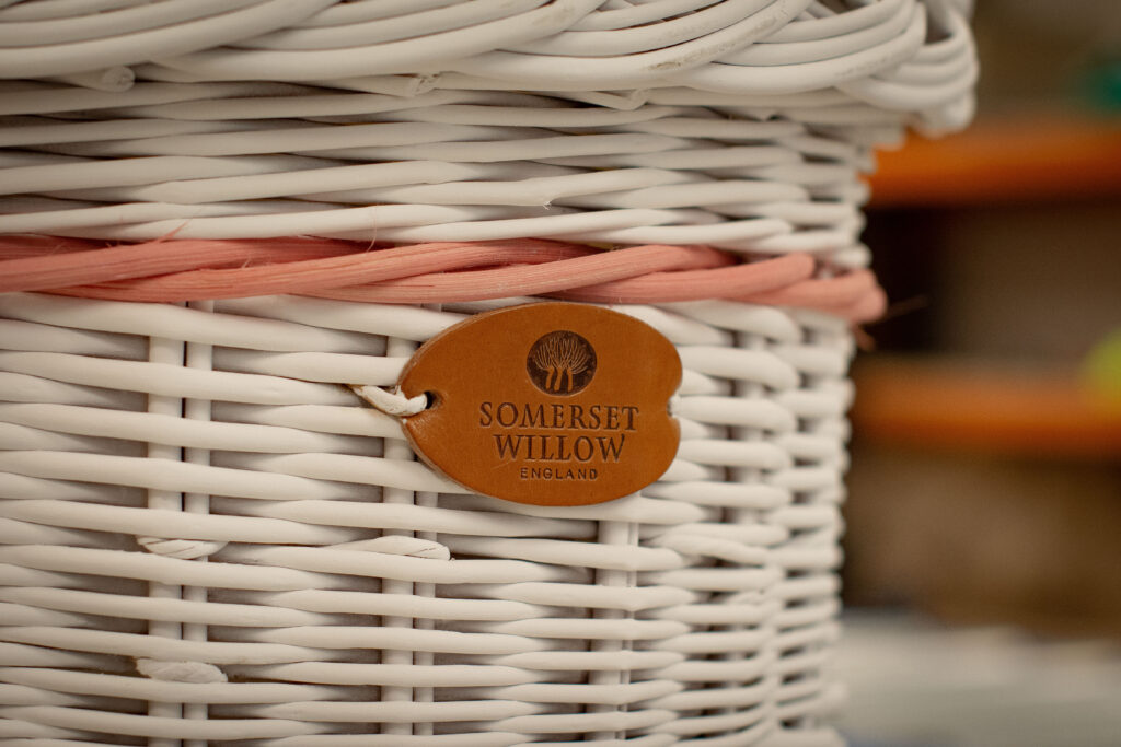 Woven willow coffin painted white with pink bands.