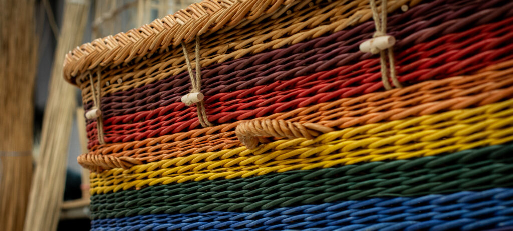 A woven willow coffin in rainbow colours.